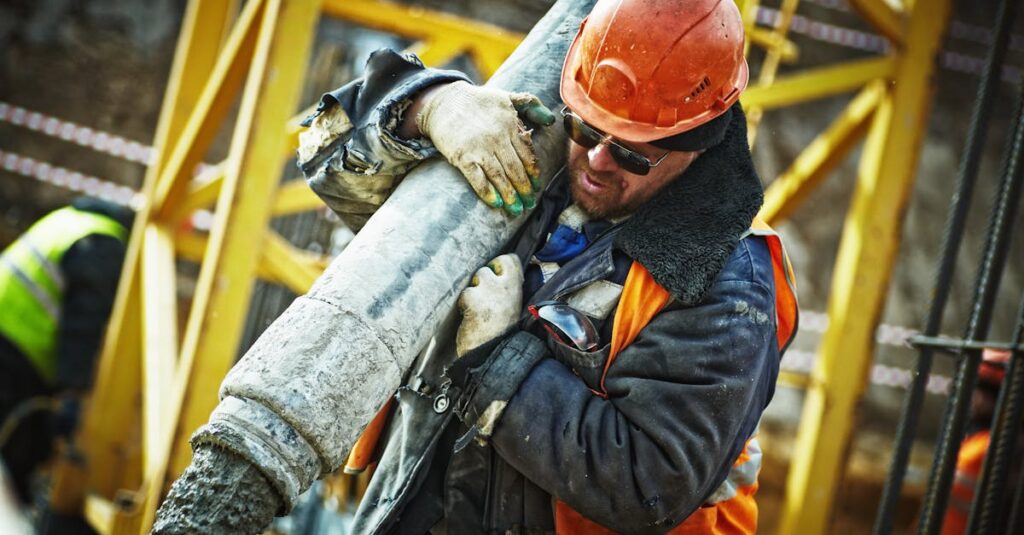 Construction worker in safety gear handling equipment on an active site.